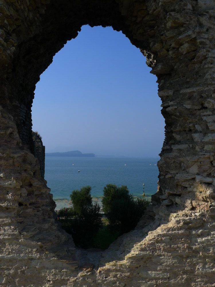 Ein Loch in der Mauer, das den Blick auf den Gardasee freigibt.