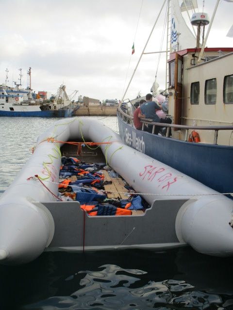 Ein Schlauchboot in grau in dem ganz viele Schwimmwesten liegen die Orange leuchten.