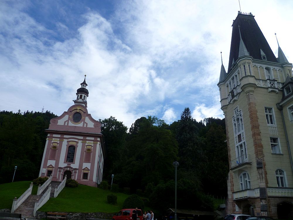 Die Rokokokapelle ist weiß mit hellroten Dekor. Sie steht auf einem Hügel nur ca. 30 m vom Schloss Mentlberg entfernt.