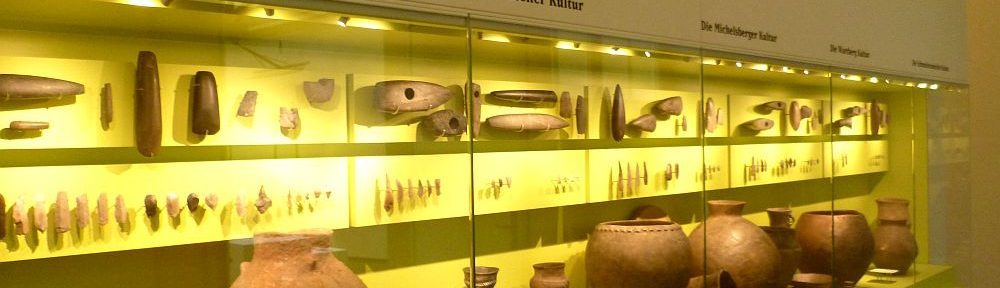 Museumsvitrinen gefüllt mit typischen Funden. In jeder Vitrine ist eine Kultur und ihre jeweilige Typologie gezeigt.