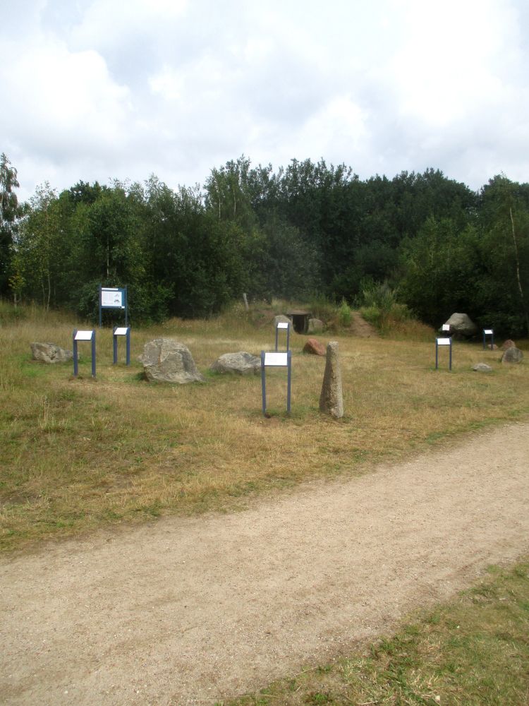 Einzelne Steine liegen auf einer Wiese. Daneben je ein Schild.