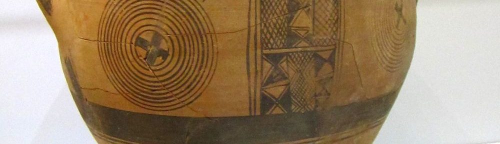 Eine Keramik mit weiter Öffnung und zwei Henkeln. Sie ist mit schwarzen Malereien verziert. Diese sind geometrische Muster, und Menschen aus Dreiecken.