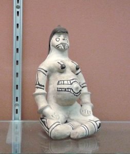 Eine Keramikpuppe einer schwangeren Frau. Es ist eine Litjoko der Karaja. Die Frau iat ganz in Weiß dargestellt und mit schwarzen strichn bemalt.
