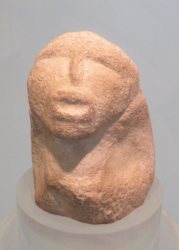 Eine Figur aus Lepenski Vir. Sie hat einen Kopf mit einem herausgearbeiteten Gesicht, der auf einem Körper sitzt, der nur auf einem Klumpen besteht.