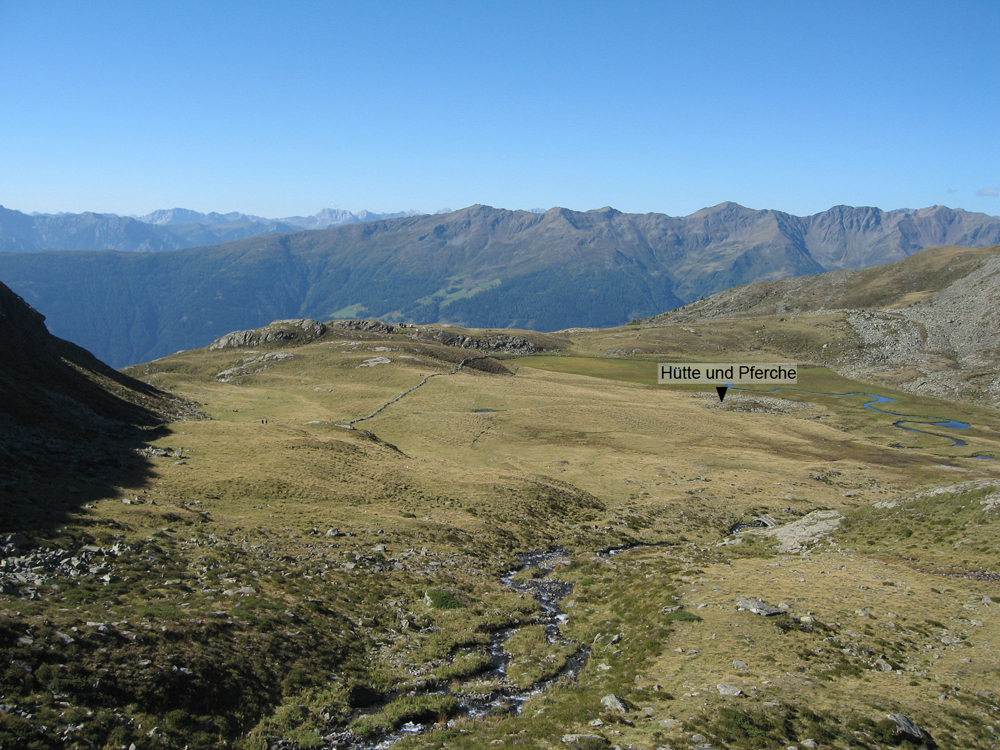 Eine Hochebene in den Alpen. Eine Weite Grün bewachsene Fläche, die plötzlich Abbricht. Dahinter befindet sich in weiter Ausblick in die Alpen.