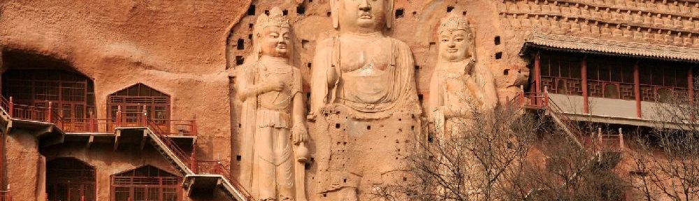 Ei Relif am Roten Sandstein, das sich über mindestens 6 Stockwerke zieht. Drei Figurn werden gzeigt. Si stehe nebeneinander. Es handelt sich um Buddhistische Figuren.