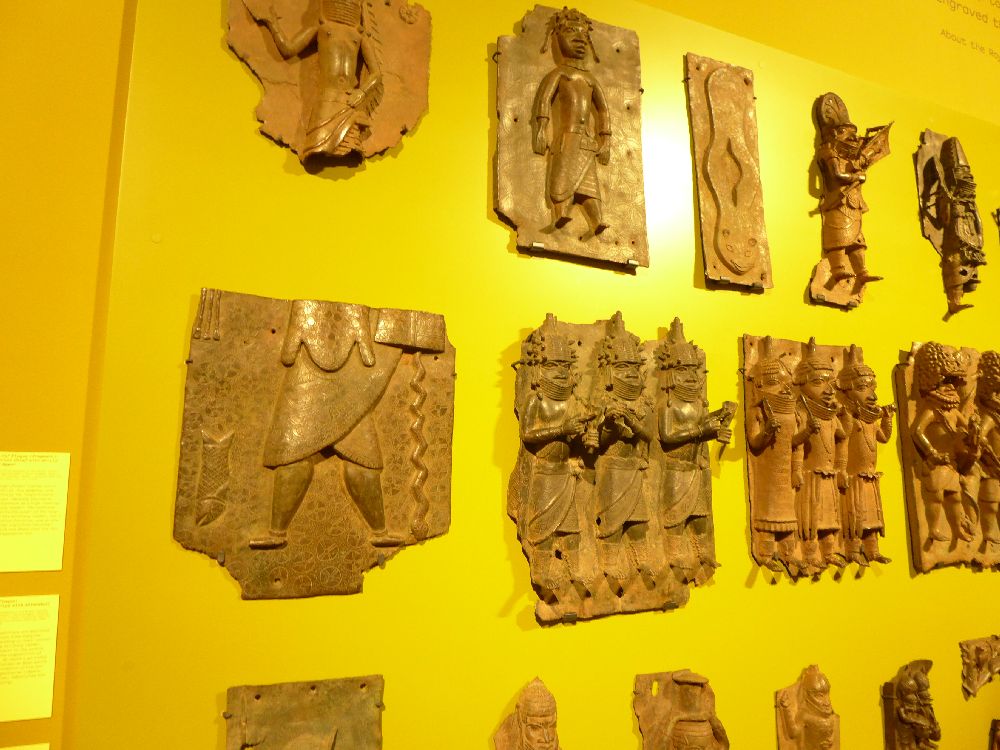 11 Reliefplatten aus Bronze an einer Wand