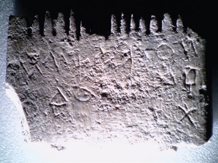 Schräg angeleuchtet, die einzelnen geritzten Schriftzeichen als Foto auf dem Kamm aus Lachisch.