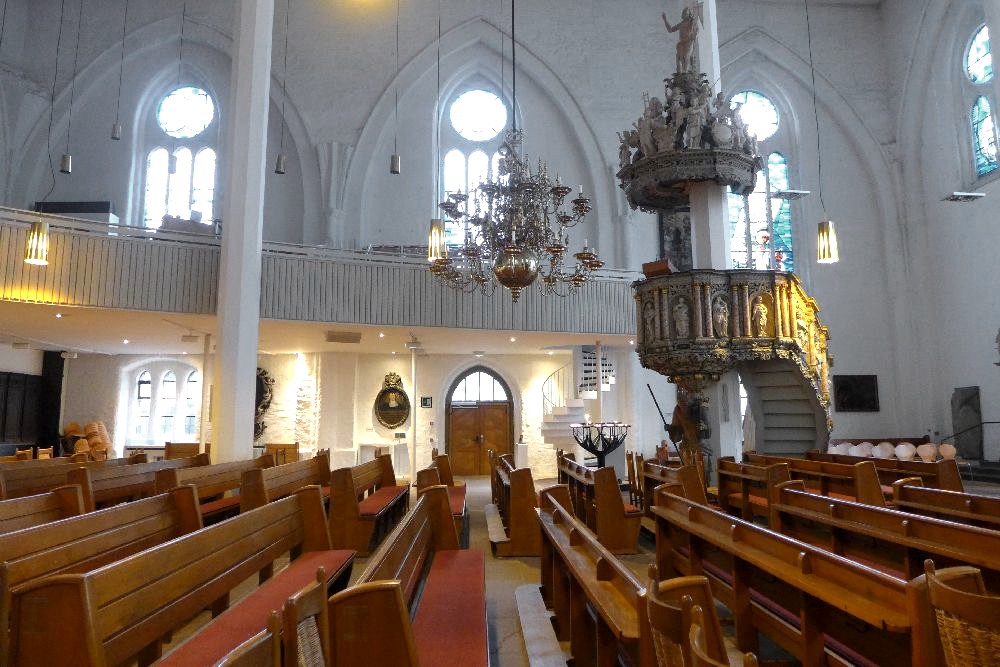 Ein Blick vom dort auf das Südschiff der Kirche von innen. Man sieht, einen Bogengang von der Seite. Eine Kanzel, und Holzbänke. Im Hintergrund adeligen Porträts.