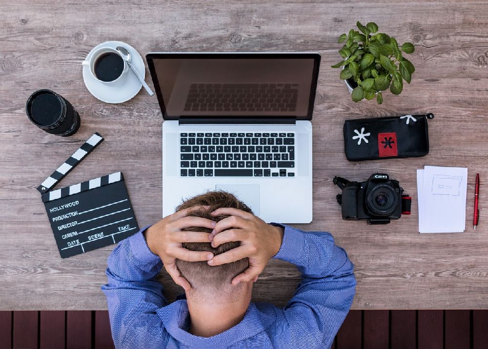 Ein Mann sitzt vor dem Laptop und schlägt verzweifelt die Hände über dem Kopf zusammen.