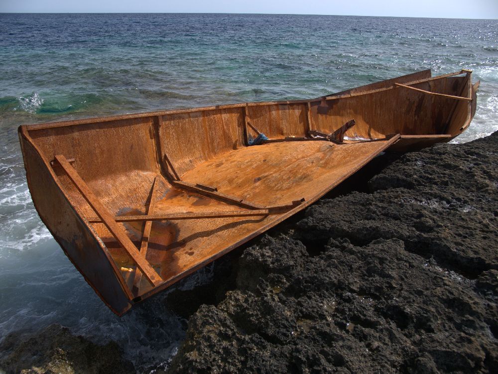 Ein total verbeultes Fluchtboot am Ufer von Lampedusa