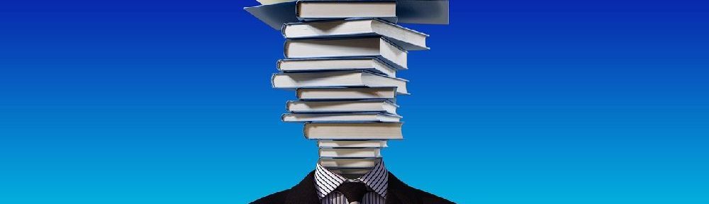 Mann steht vor einer blauen Wand. Er hat keinen Kopf, dafür besteht er aus einem Stapel Bücher.