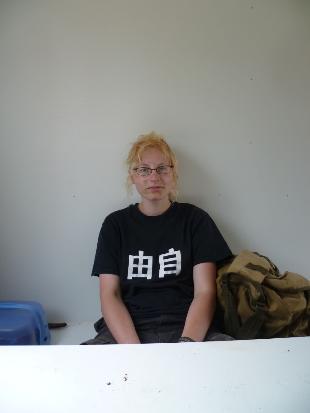 Eine Frau mit dreckigem Gesicht sitzt und guckt müde in die Kamera.
